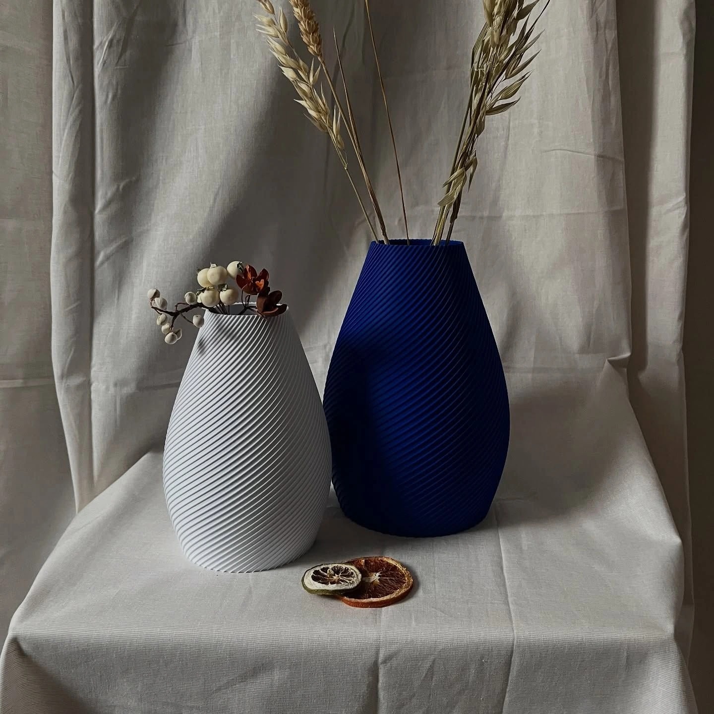 White and cobalt Vertigo vases with dried grasses on a linen-covered table